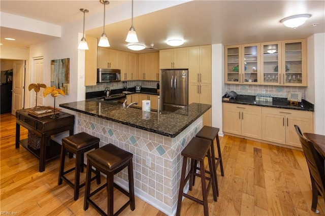 kitchen with a kitchen breakfast bar, stainless steel appliances, light hardwood / wood-style flooring, and tasteful backsplash