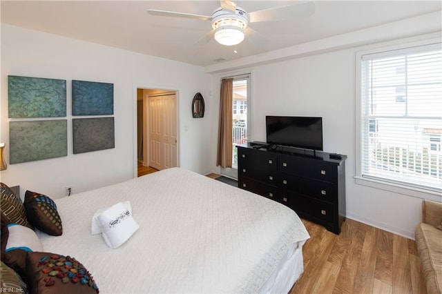 bedroom with ceiling fan, multiple windows, and light hardwood / wood-style flooring