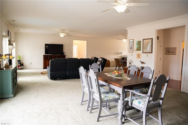 dining area with crown molding, ceiling fan, and light colored carpet