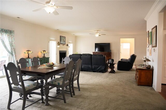 carpeted dining space featuring crown molding and ceiling fan