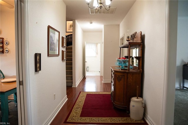 hallway with dark hardwood / wood-style flooring and a chandelier