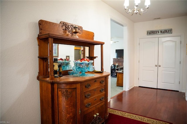 hallway with an inviting chandelier and dark carpet