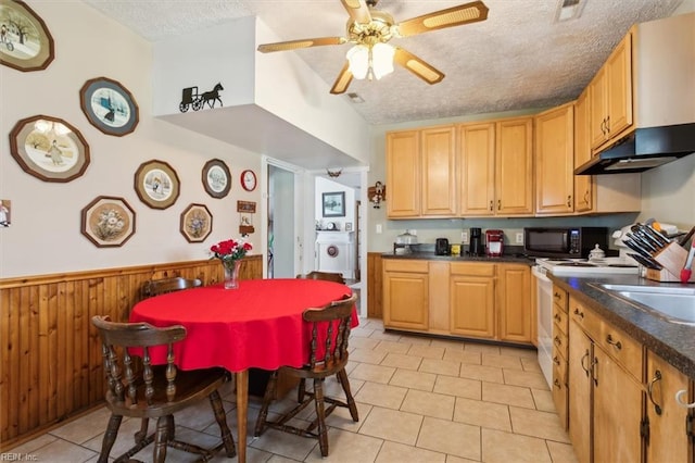 kitchen featuring ceiling fan, wall chimney range hood, light tile flooring, and a textured ceiling