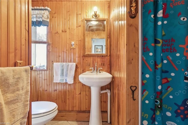 bathroom featuring tile floors, toilet, wooden walls, and sink