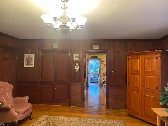 sitting room featuring wooden walls, light hardwood / wood-style floors, and a notable chandelier