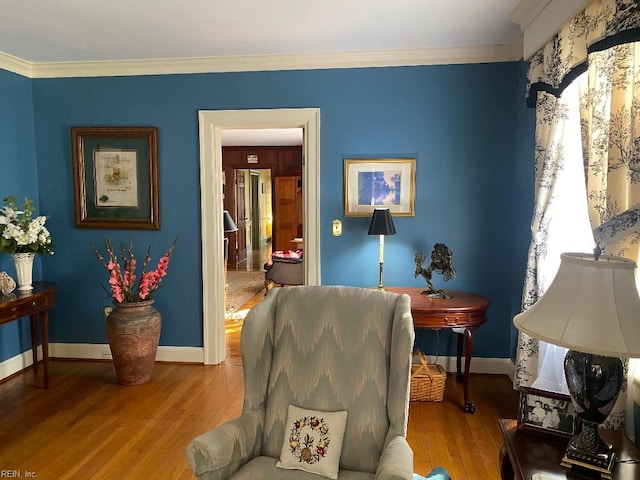 sitting room with ornamental molding and light wood-type flooring