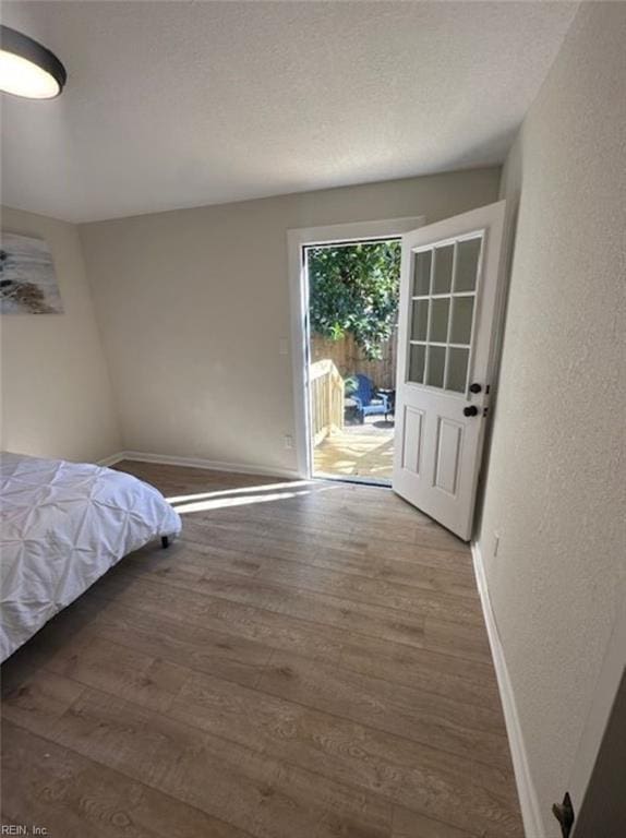 unfurnished bedroom with access to exterior and hardwood / wood-style floors