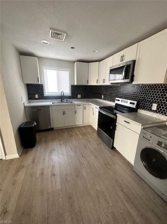 kitchen with white cabinets, sink, hardwood / wood-style flooring, and stainless steel appliances