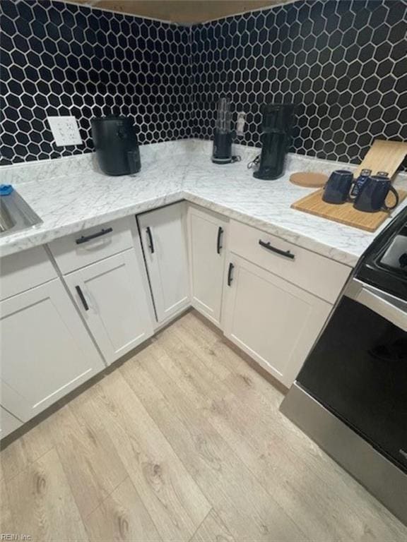 kitchen with white cabinets, light wood-type flooring, and light stone counters