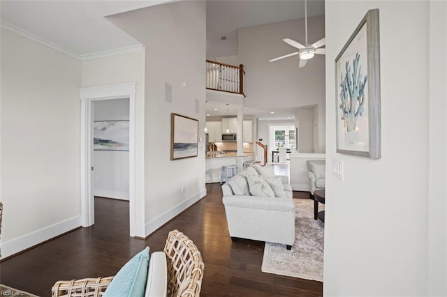 living room with ornamental molding, ceiling fan, dark wood-type flooring, and a high ceiling