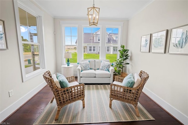 living area with a notable chandelier, dark hardwood / wood-style floors, and ornamental molding