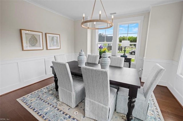 dining area with light hardwood / wood-style floors, ornamental molding, and a chandelier