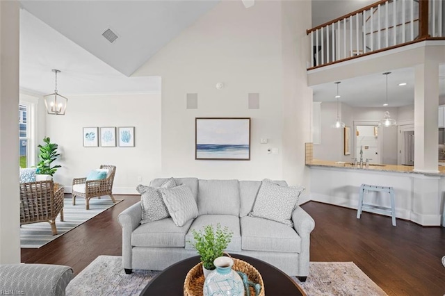 living room with dark hardwood / wood-style flooring, an inviting chandelier, and high vaulted ceiling