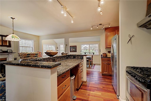 kitchen with dark stone counters, appliances with stainless steel finishes, light hardwood / wood-style floors, a kitchen island, and rail lighting