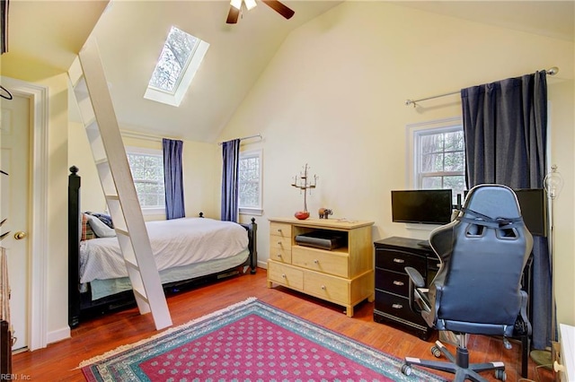 bedroom with dark hardwood / wood-style flooring, ceiling fan, high vaulted ceiling, and a skylight