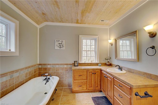 bathroom with plenty of natural light, a bath to relax in, tile floors, and vanity with extensive cabinet space