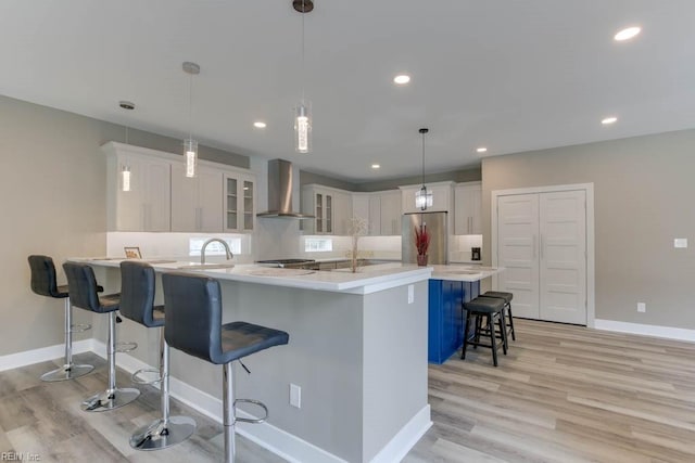 315 Dare Rd, Yorktown, VA 23692 - kitchen with stainless steel refrigerator, a breakfast bar area, light hardwood / wood-style flooring, wall chimney range hood, and hanging light fixtures