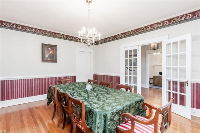 dining space featuring light hardwood / wood-style flooring, a chandelier, and french doors