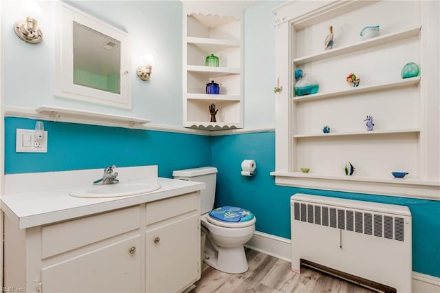 bathroom with radiator heating unit, toilet, hardwood / wood-style flooring, and vanity