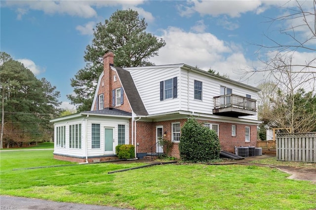 view of front of property featuring central AC unit, a front lawn, and a balcony