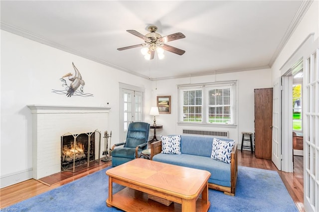 living room with ceiling fan, ornamental molding, dark hardwood / wood-style flooring, a fireplace, and radiator heating unit