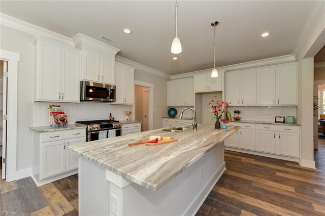 kitchen featuring stainless steel appliances, a center island with sink, white cabinetry, backsplash, and sink