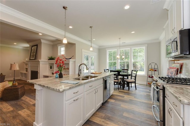 kitchen with pendant lighting, a kitchen island with sink, stainless steel appliances, and sink