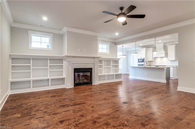 unfurnished living room featuring plenty of natural light, dark hardwood / wood-style floors, ceiling fan, and a fireplace