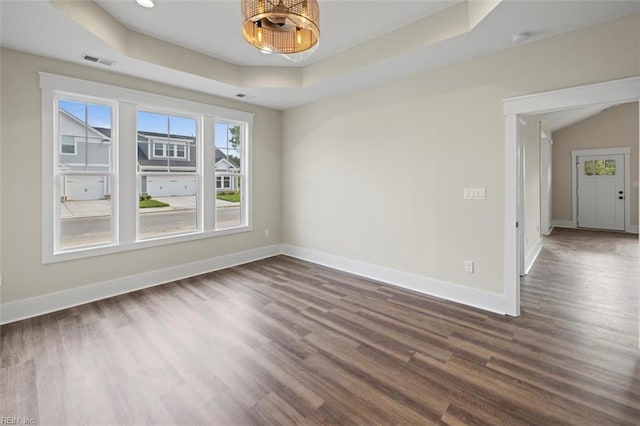 unfurnished room featuring a raised ceiling and dark wood-type flooring