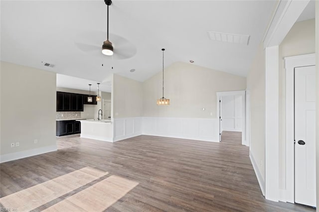 unfurnished living room featuring ceiling fan with notable chandelier, hardwood / wood-style floors, vaulted ceiling, and sink