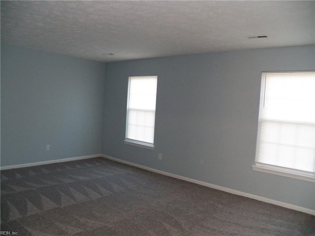 empty room featuring a textured ceiling and dark carpet