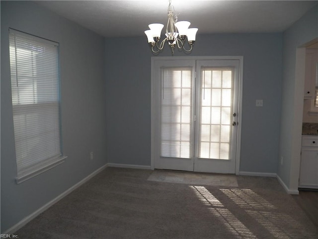 unfurnished room featuring dark carpet and a notable chandelier