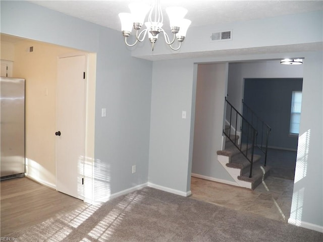 carpeted empty room featuring a notable chandelier