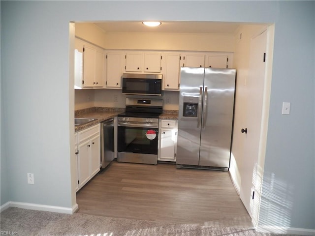 kitchen featuring appliances with stainless steel finishes, wood-type flooring, sink, and white cabinets