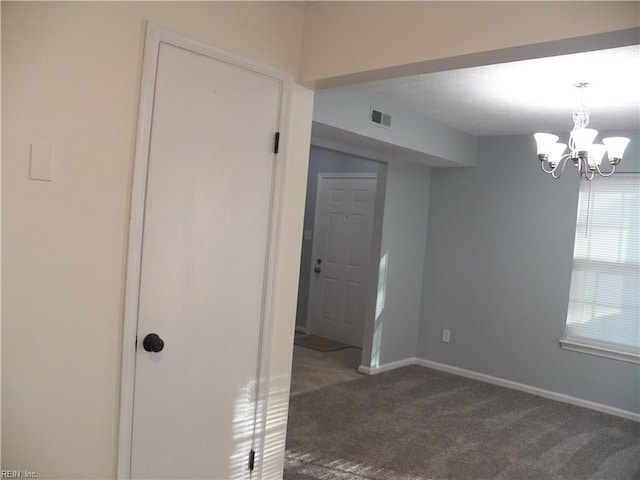 carpeted empty room with an inviting chandelier