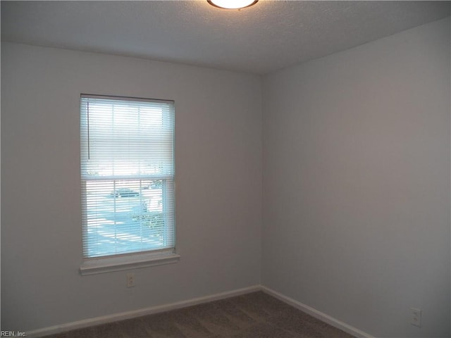 carpeted empty room featuring a textured ceiling