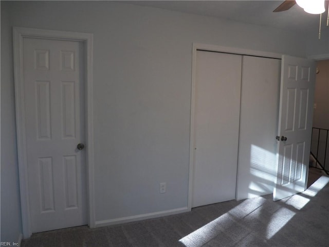 unfurnished bedroom featuring a closet, dark colored carpet, and ceiling fan