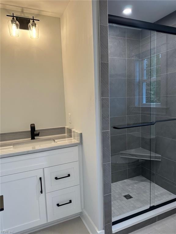 bathroom with a shower with door, vanity, and tile patterned flooring