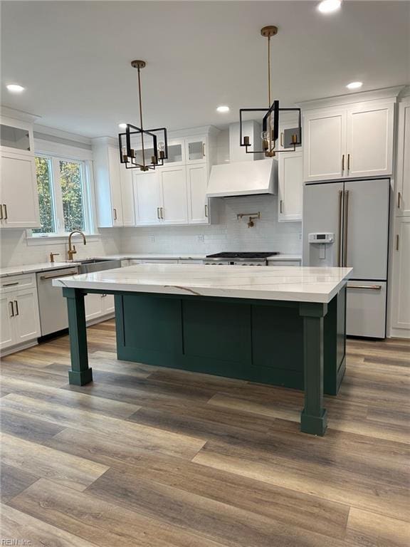 kitchen featuring appliances with stainless steel finishes, decorative light fixtures, light hardwood / wood-style flooring, white cabinets, and a center island