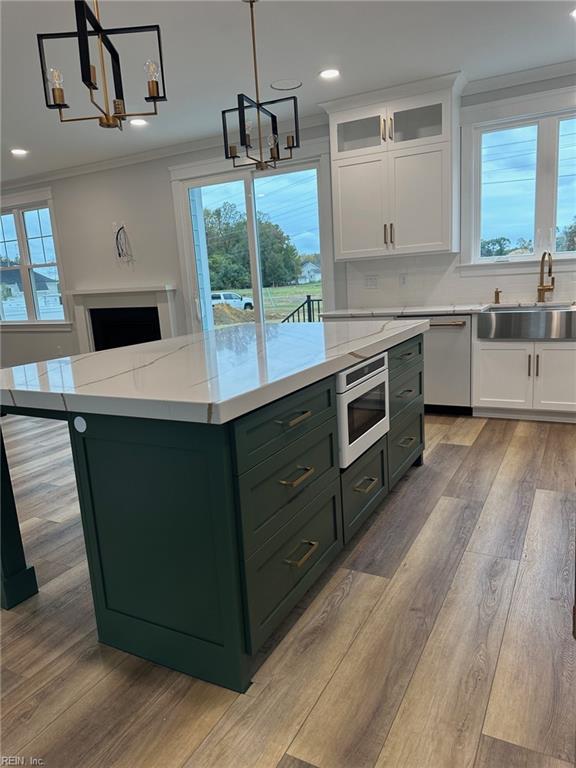 kitchen with decorative light fixtures, a center island, white cabinetry, and sink