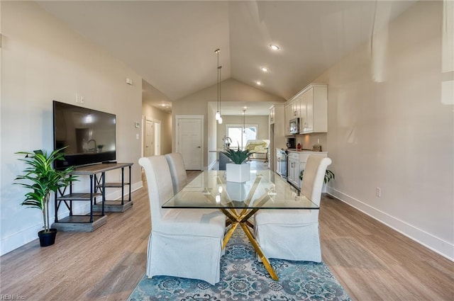 dining area with high vaulted ceiling and light hardwood / wood-style flooring