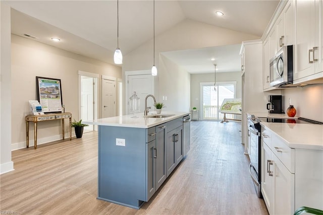 kitchen featuring sink, stainless steel appliances, vaulted ceiling, a center island with sink, and white cabinets