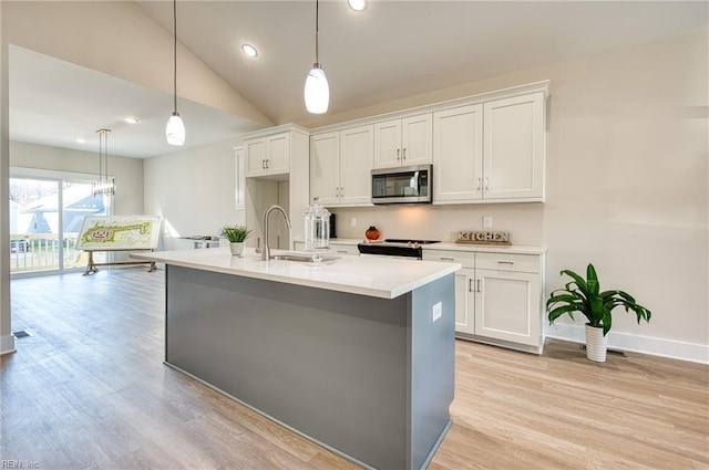 kitchen featuring decorative light fixtures, white cabinetry, sink, and an island with sink