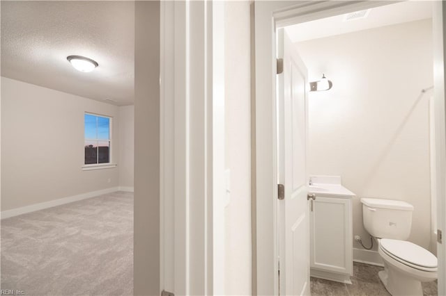 bathroom with vanity, toilet, and a textured ceiling