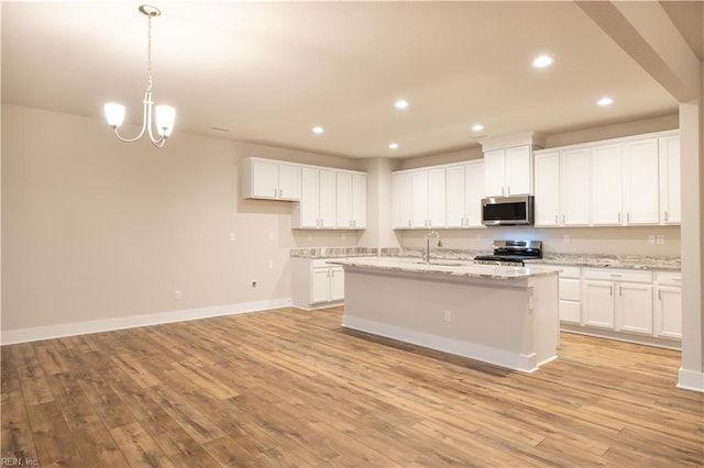 kitchen with white cabinets, appliances with stainless steel finishes, light stone countertops, and light hardwood / wood-style flooring