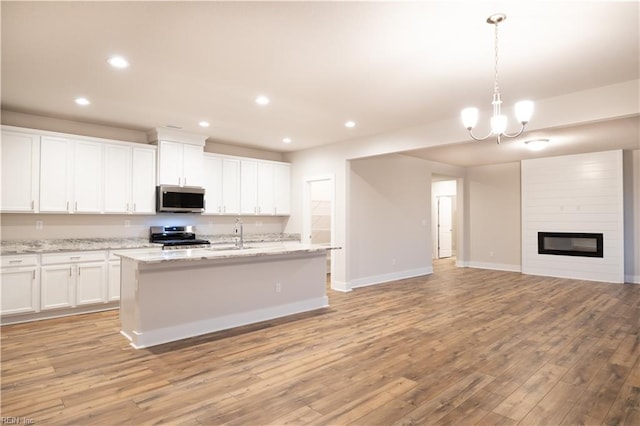 kitchen with white cabinetry, stainless steel appliances, light stone counters, and decorative light fixtures