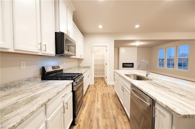 kitchen featuring light stone countertops, light hardwood / wood-style floors, sink, appliances with stainless steel finishes, and white cabinets