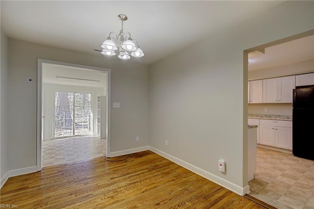 unfurnished dining area with light hardwood / wood-style floors and a notable chandelier