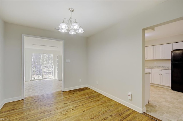 unfurnished dining area with a chandelier and light wood-type flooring