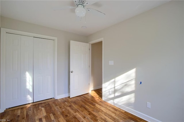 unfurnished bedroom featuring hardwood / wood-style floors, a closet, and ceiling fan